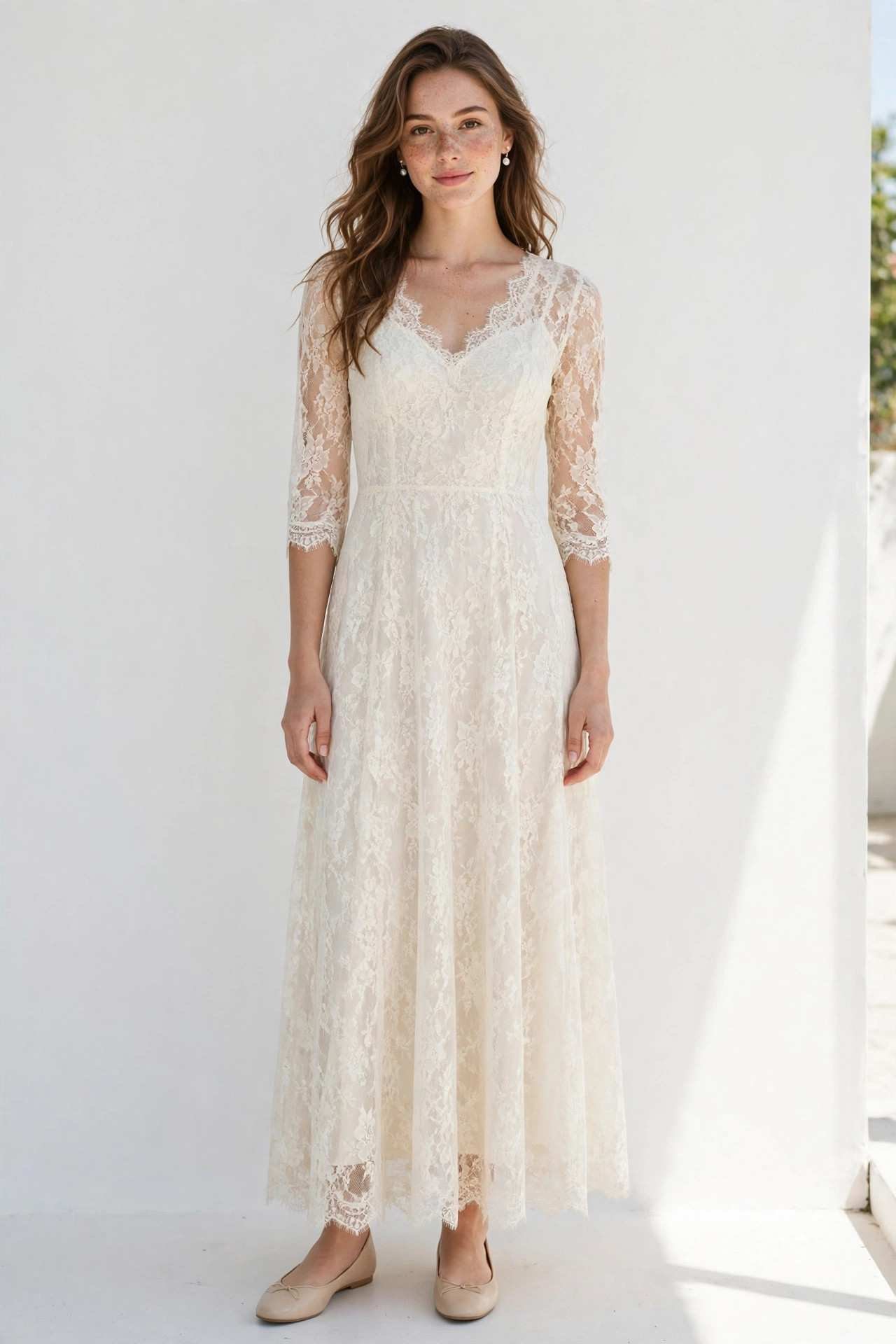 Woman wearing an ivory lace dress with pearl earrings