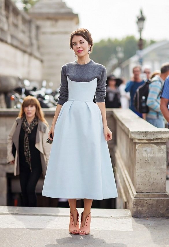 Woman layering a sweater over a casual dress