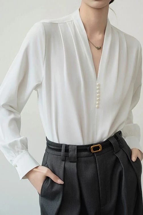 Woman in a white blouse with pearl buttons and navy trousers