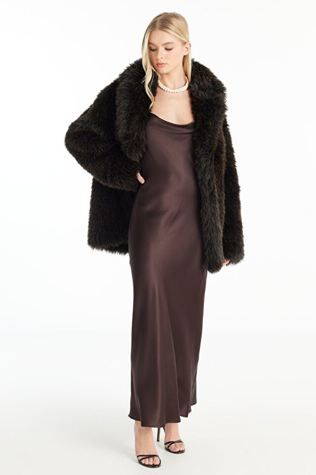 Woman in brown fur coat sitting on a sofa