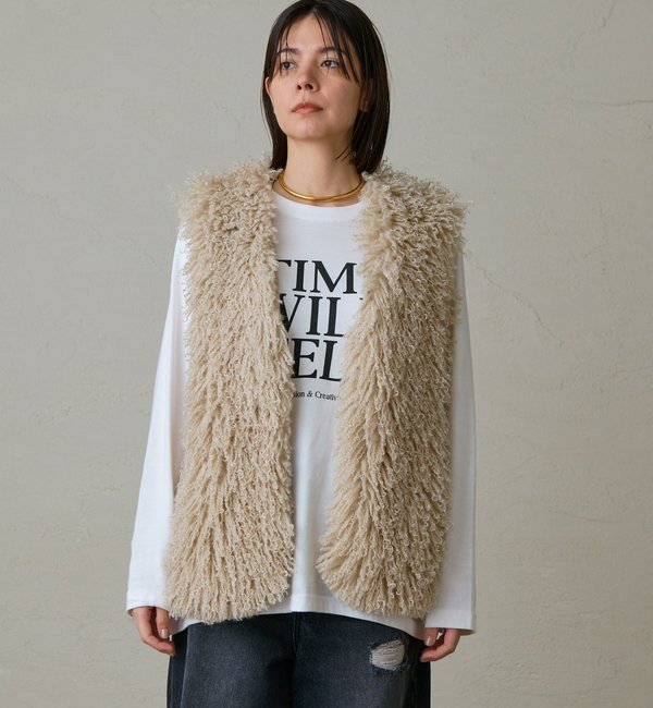 Woman wearing a faux fur vest over a long-sleeve top