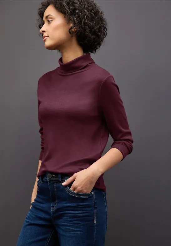 Woman in burgundy turtleneck sweater and vintage wash jeans