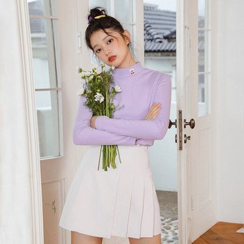 Woman in lavender turtleneck sweater with pleated tennis skirt