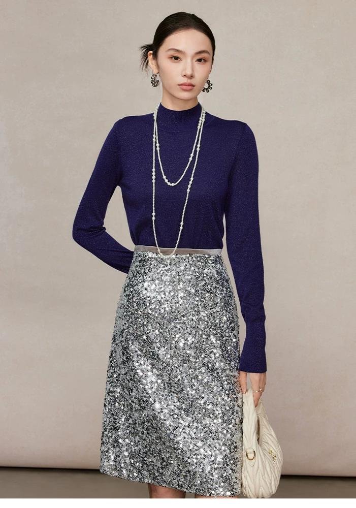 Woman in navy turtleneck sweater with silver metallic skirt