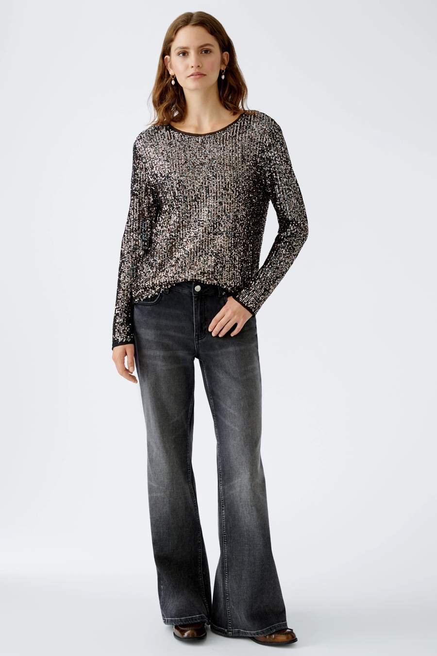 Woman in wide-leg jeans with a sparkly top at a New Year party