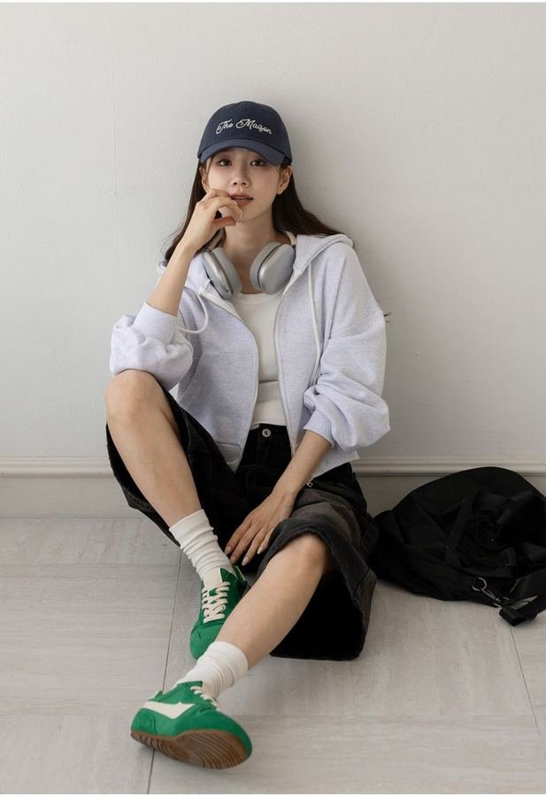 Woman in a hoodie with a denim mini skirt and sneakers