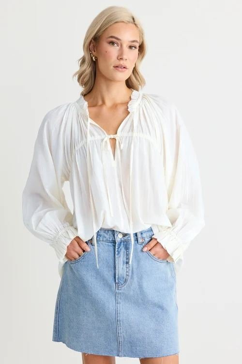 Woman in a breezy blouse with a light-wash denim mini skirt