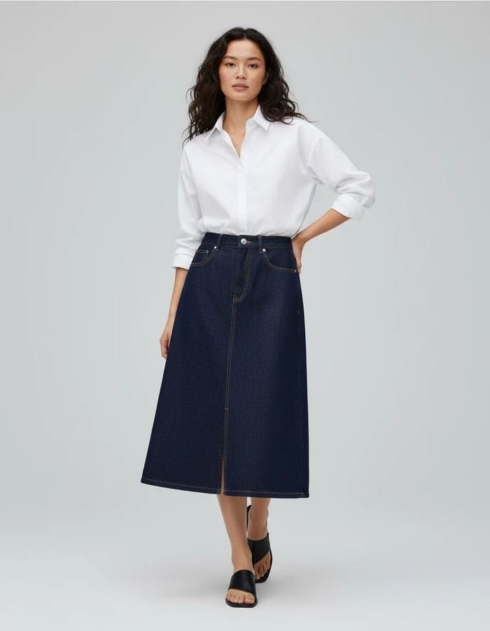 Woman in a white button-down shirt with a dark-wash denim midi skirt