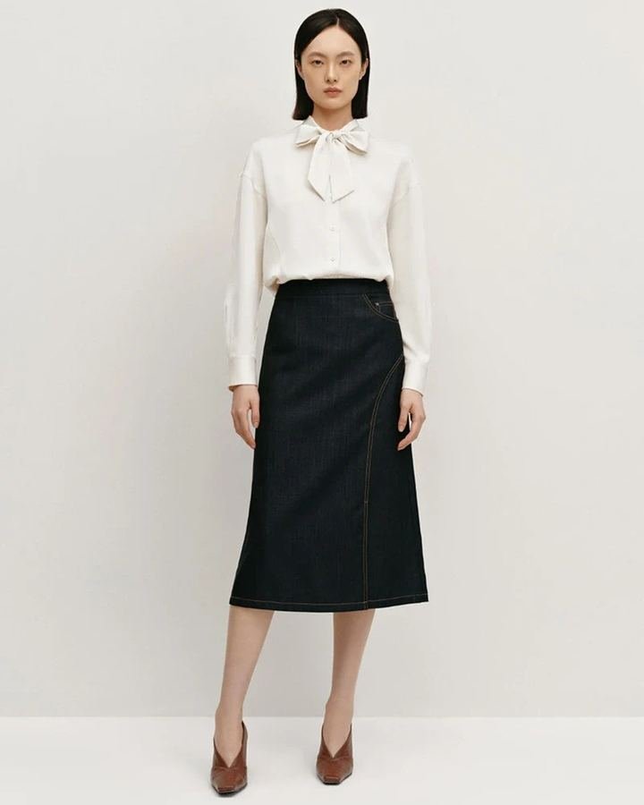 Woman wearing a silk blouse with a denim pencil skirt