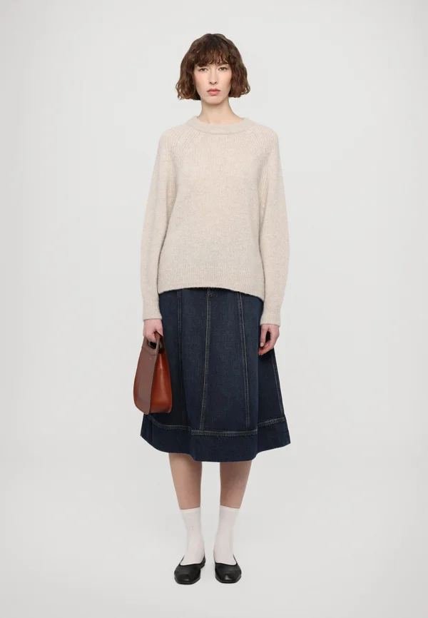 Woman in a fine-knit sweater with a tailored denim midi skirt