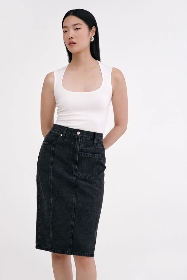 Woman in a white shell top with a black denim pencil skirt