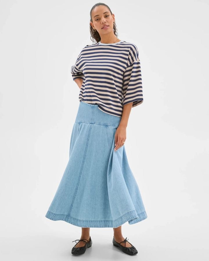 Woman in a Breton stripe top with a denim midi skirt and flats