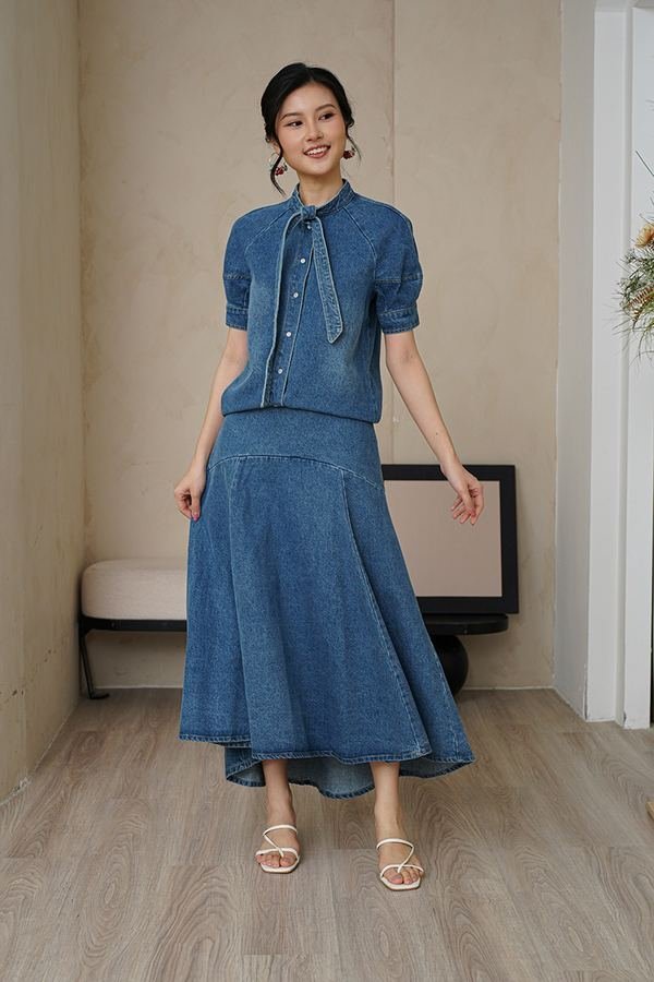 Woman in an elegant draped top with a denim midi skirt