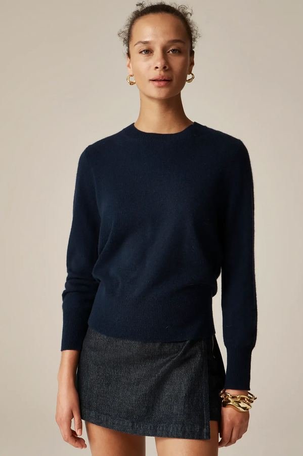 Woman in a cashmere crewneck sweater with a denim midi skirt