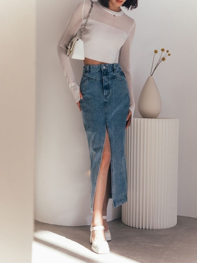 Woman in a silk top with a slit denim midi skirt