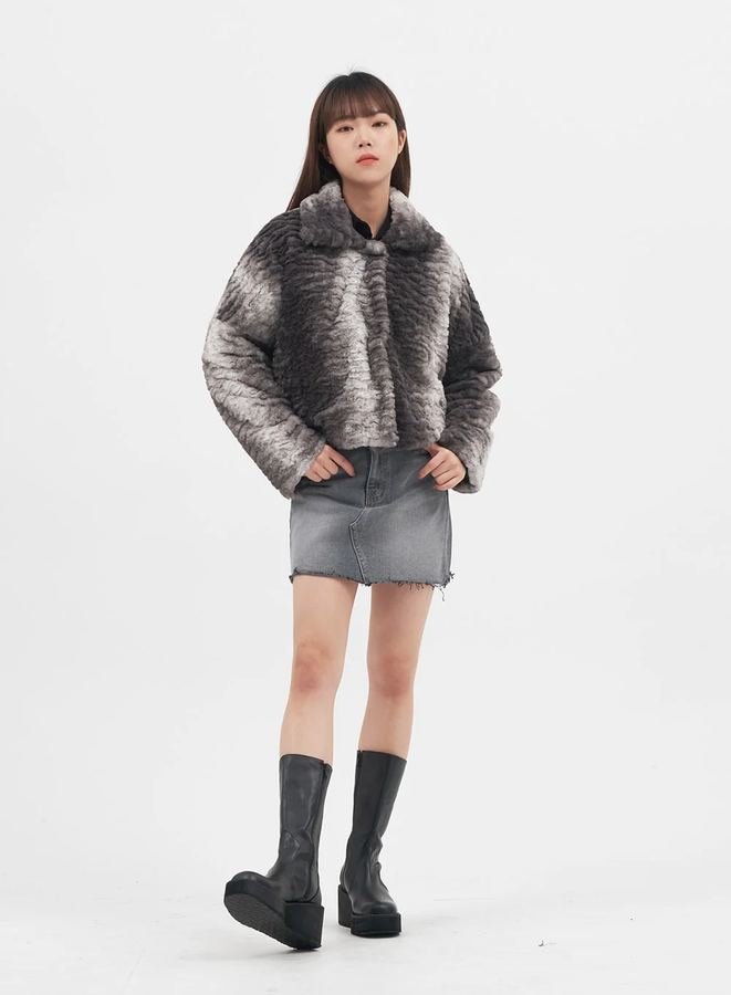 Woman in a cropped faux-fur jacket with a denim mini skirt