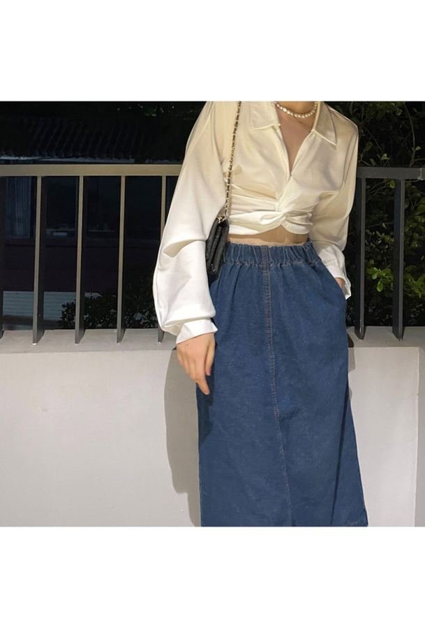 Woman in a satin shirt with a dark denim skirt at night in the city