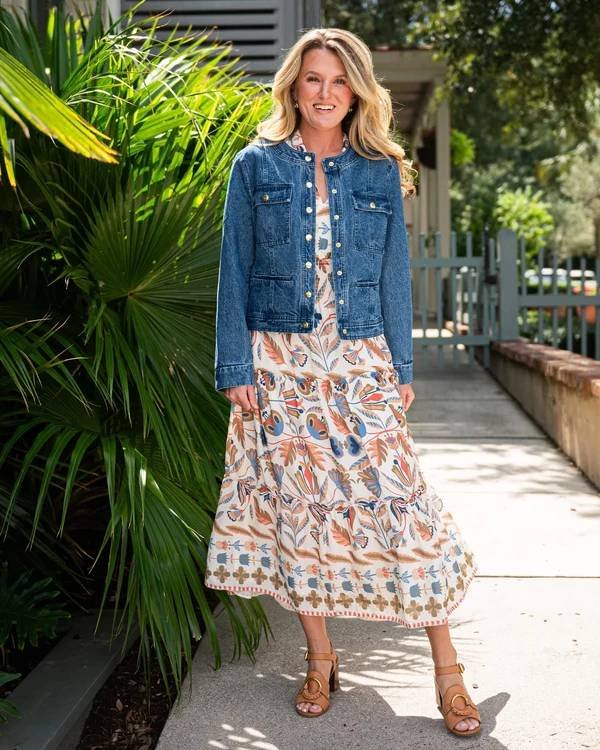 Woman in a denim jacket over a floral maxi dress