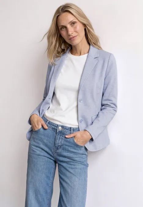 Woman in light-wash jeans and a pastel blazer