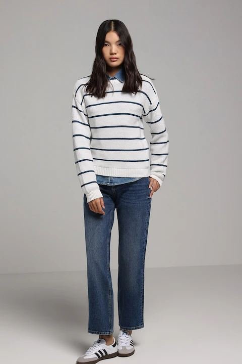 Woman in a striped knit sweater and white sneakers