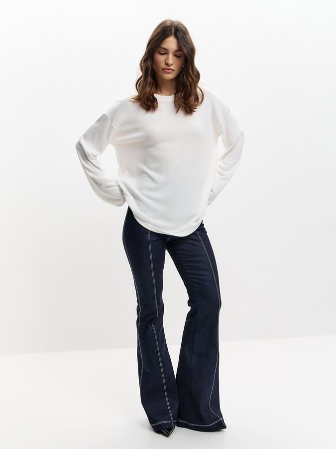 Woman in a lightweight knit top and flare jeans