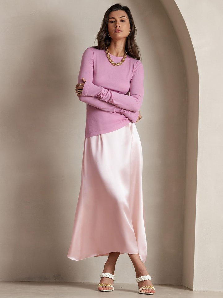woman in blush sweater and champagne satin midi skirt at a romantic dinner