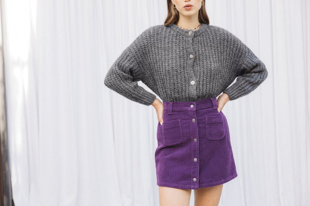 woman in chunky knit cardigan and corduroy mini skirt with knee-high boots in fall