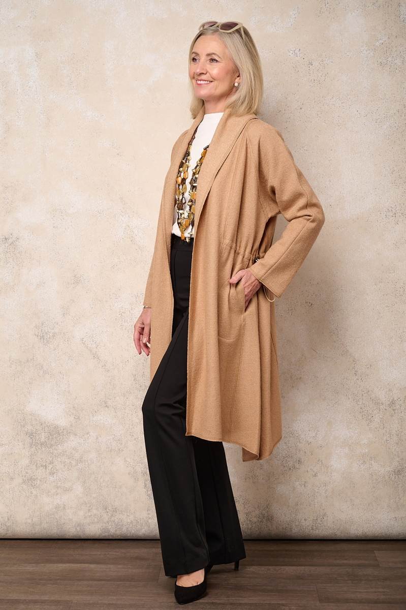 woman in long camel duster cardigan over black slim pants at dinner