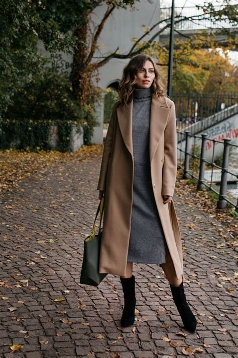 woman in camel coat over burgundy sweater dress with black ankle boots