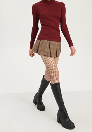 woman in burgundy plaid skirt with chunky black chelsea boots and tights