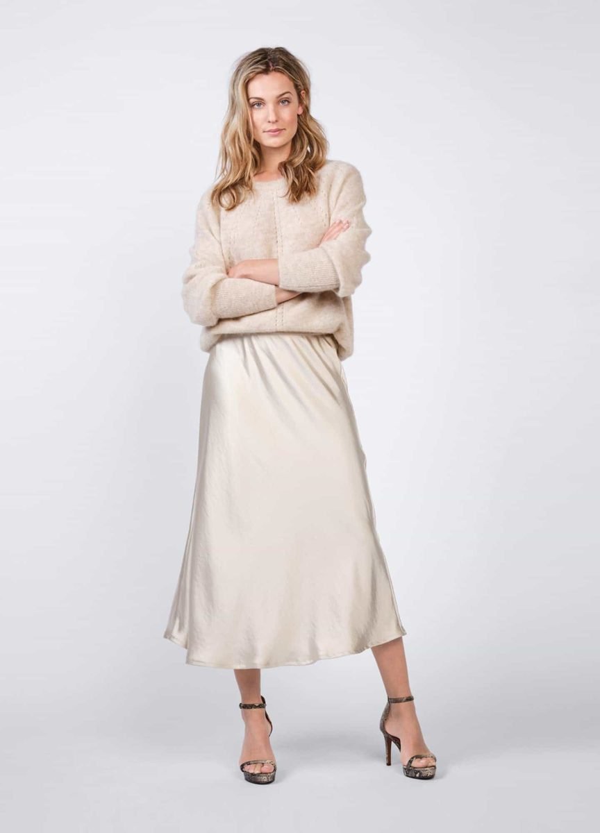 Woman wearing a taupe satin midi skirt with a cashmere sweater